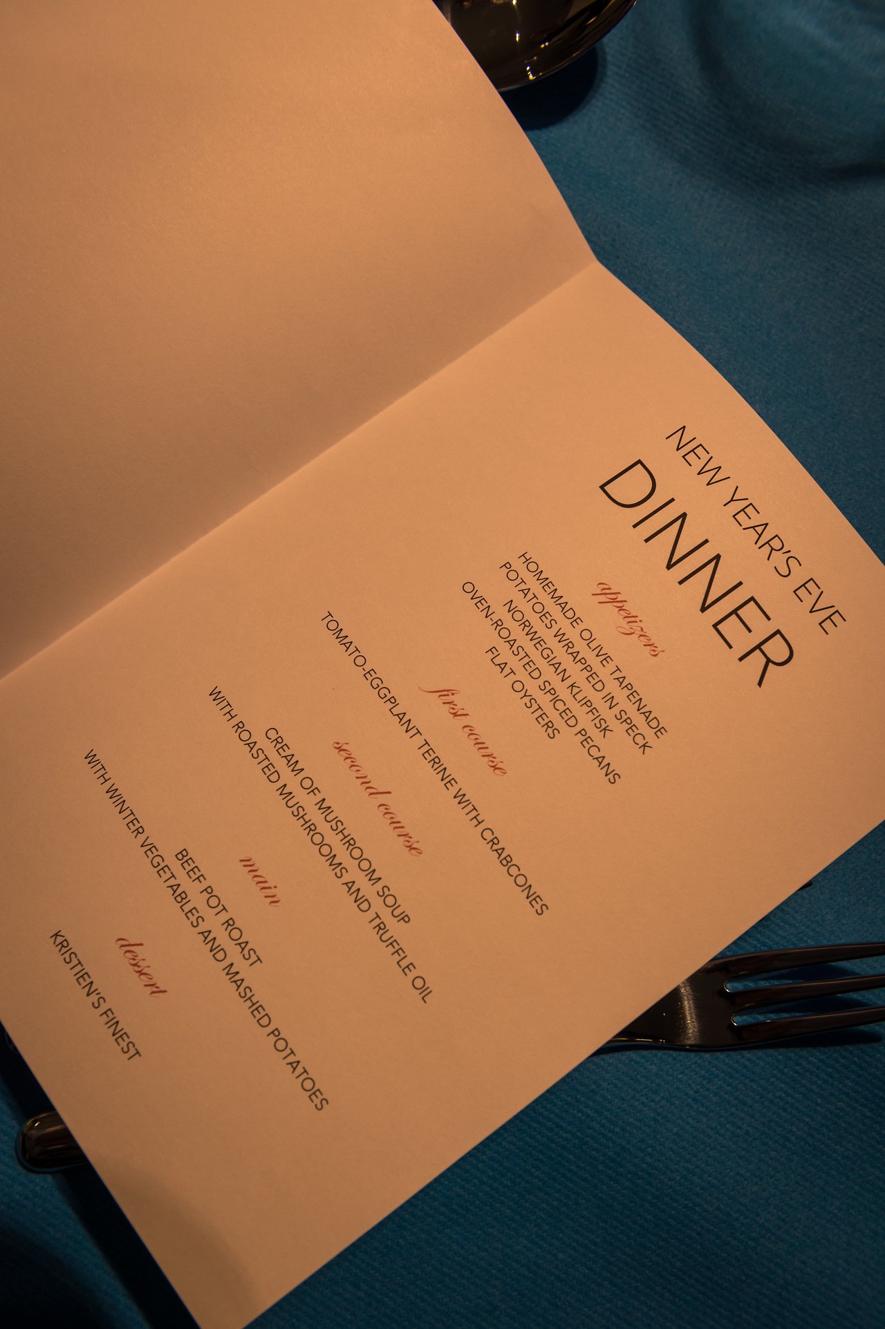 A New Year's Eve dinner menu is open on a table, listing appetizers, main courses, and dessert options.