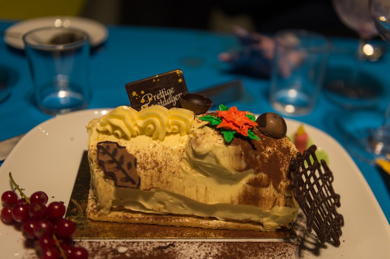 A festive dessert with chocolate decorations and a "Prettige Feestdagen" sign on a plate at a New Year's Eve party.