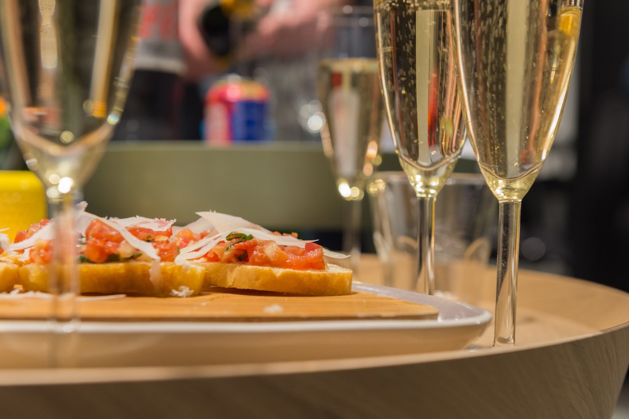 Glasses of champagne and a plate of bruschetta on a table at a New Year's Eve party.
