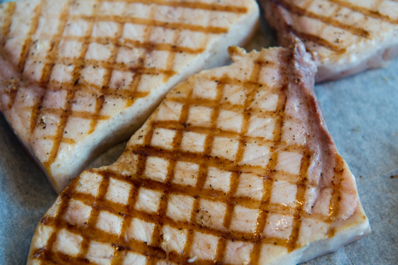 Grilled pork chops with seared grill marks on a surface, seasoned with spices.