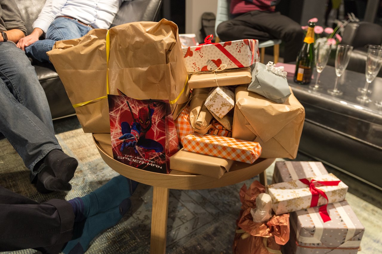 A table filled with wrapped gifts, including a Spider-Man bag, at a New Year's Eve party.