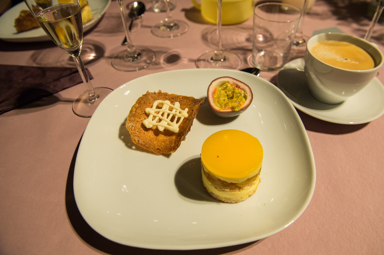 A plate with desserts, including a layered cake, a crispy pastry with cream, and half a passion fruit.