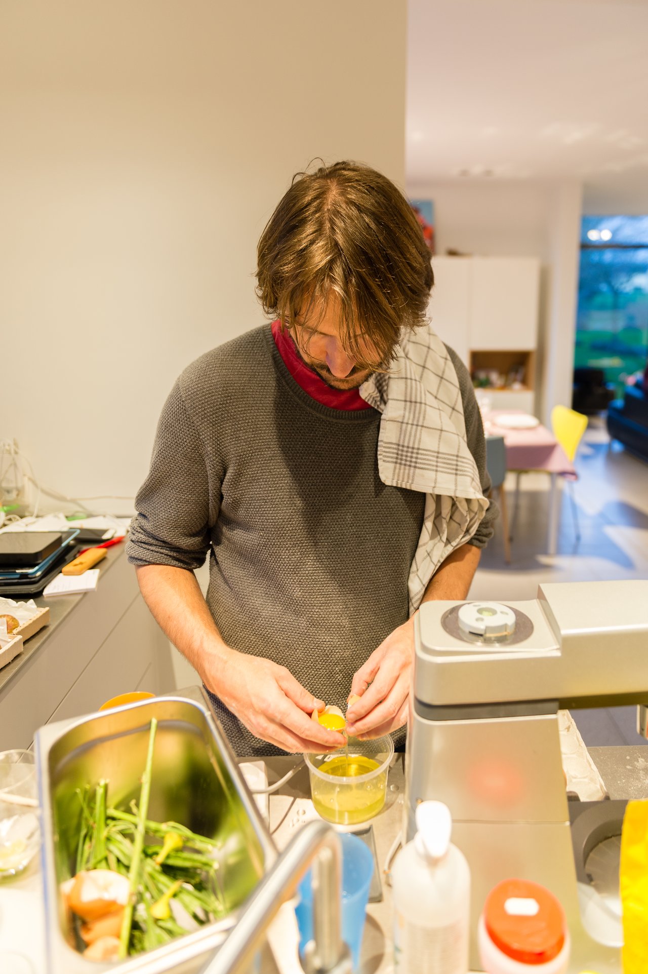 A person in a kitchen cracks an egg into a container while preparing food for a New Year's Eve party.