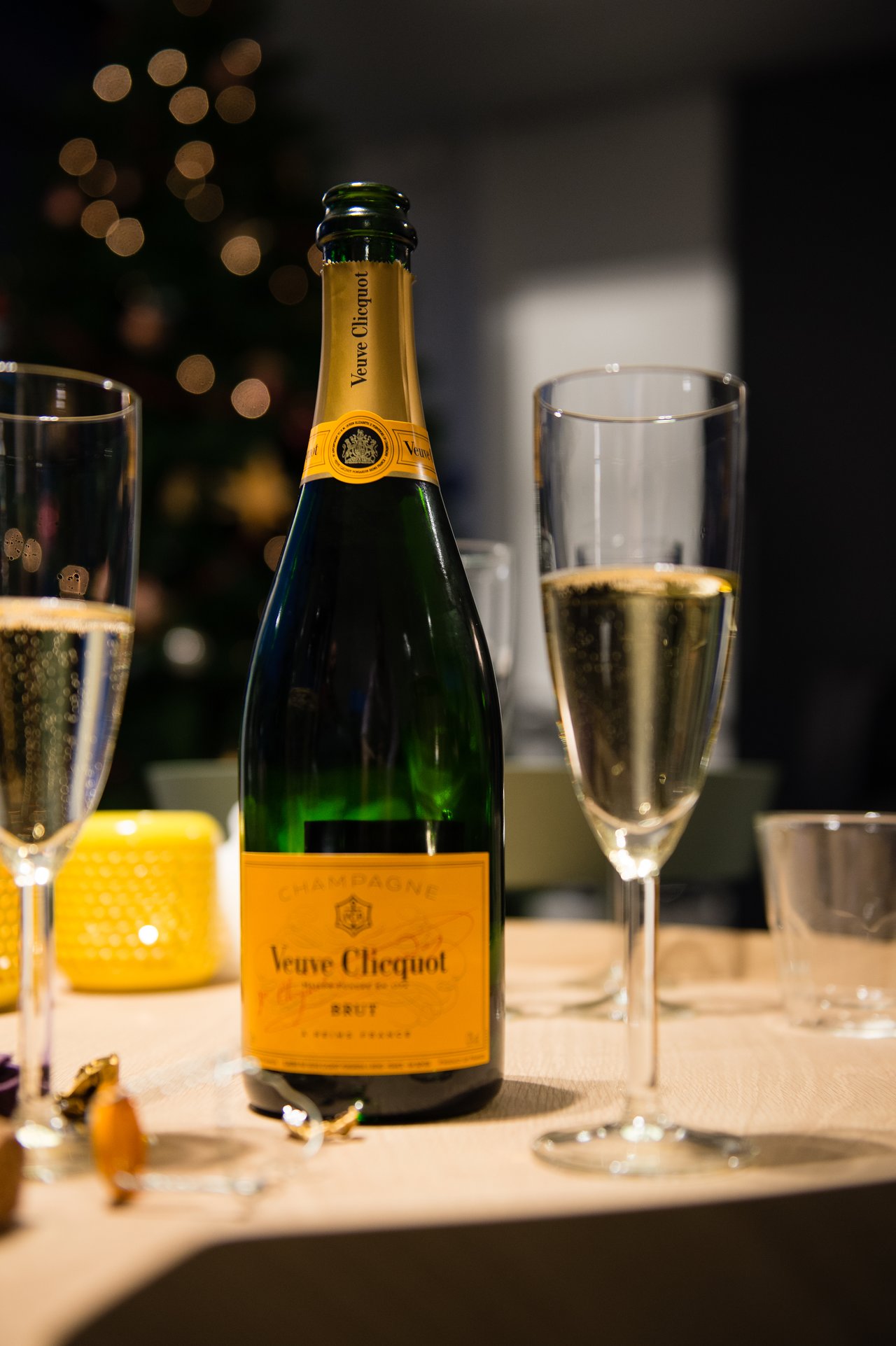 A bottle of champagne on a table with two filled glasses, ready for a New Year's Eve celebration.
