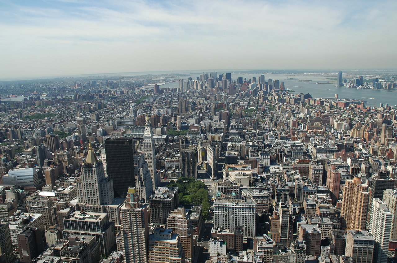 Aerial view of New York City with skyscrapers, streets, and the waterfront in the distance.