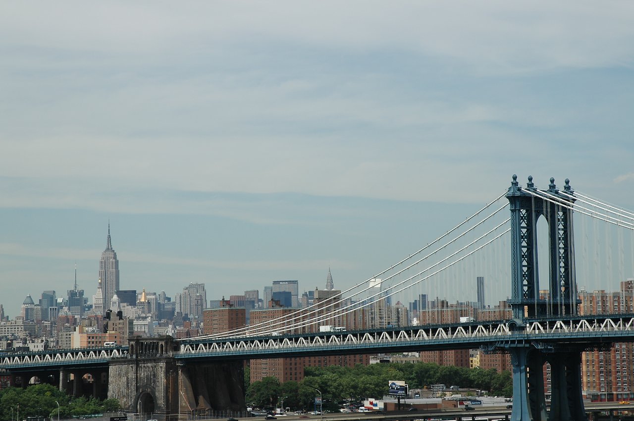 The Manhattan Bridge with the New York City skyline, including the Empire State Building, in the background.