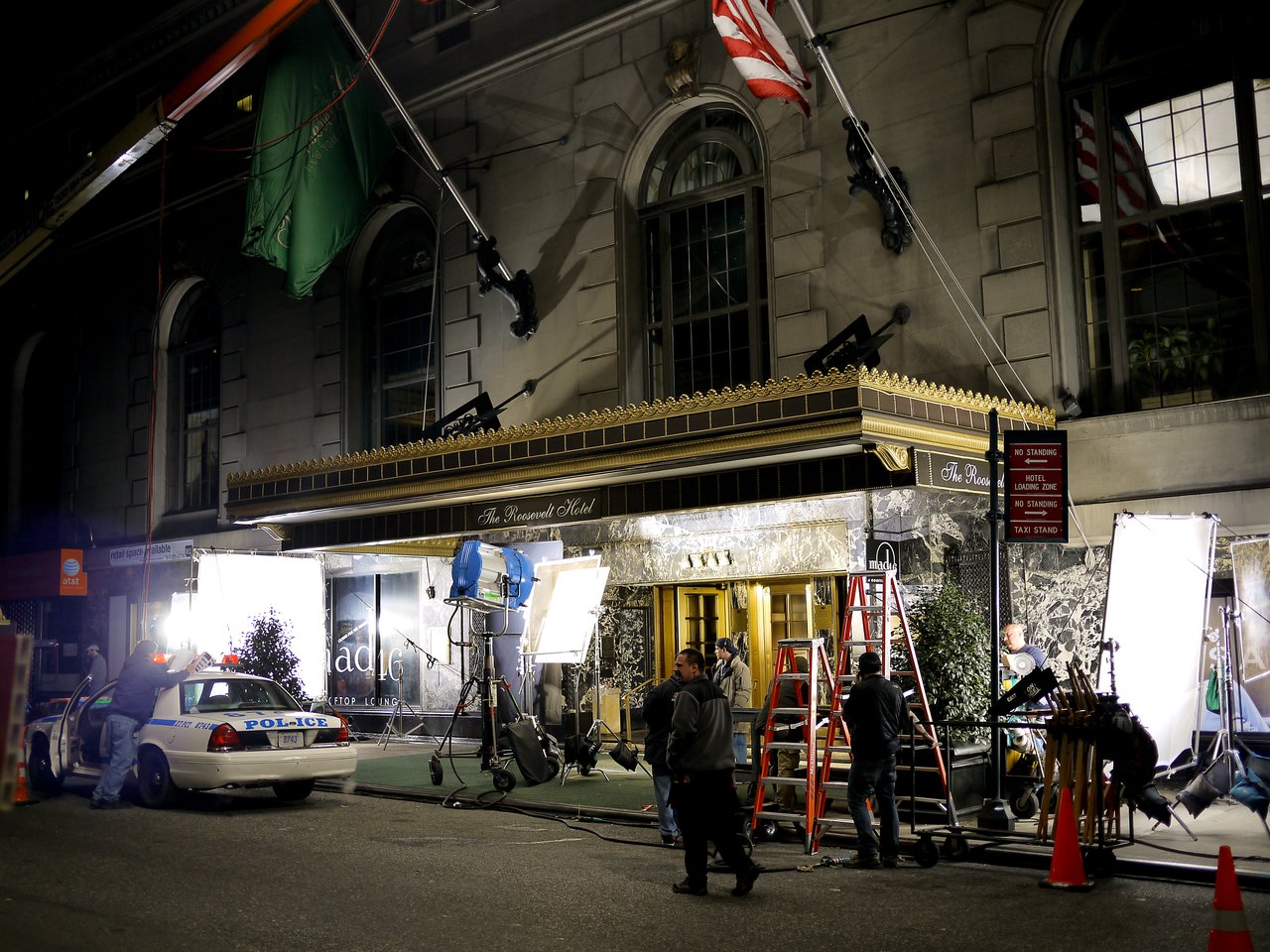 Film crew setting up lights and equipment outside the Roosevelt Hotel for a nighttime movie shoot.