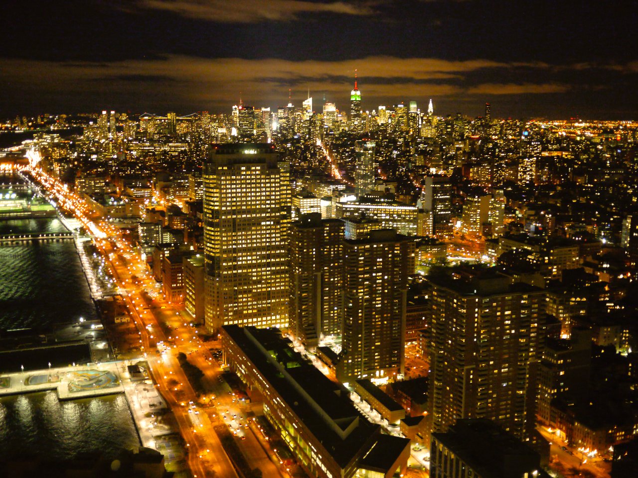 A nighttime view of the New York City skyline with illuminated buildings and streets stretching into the distance.
