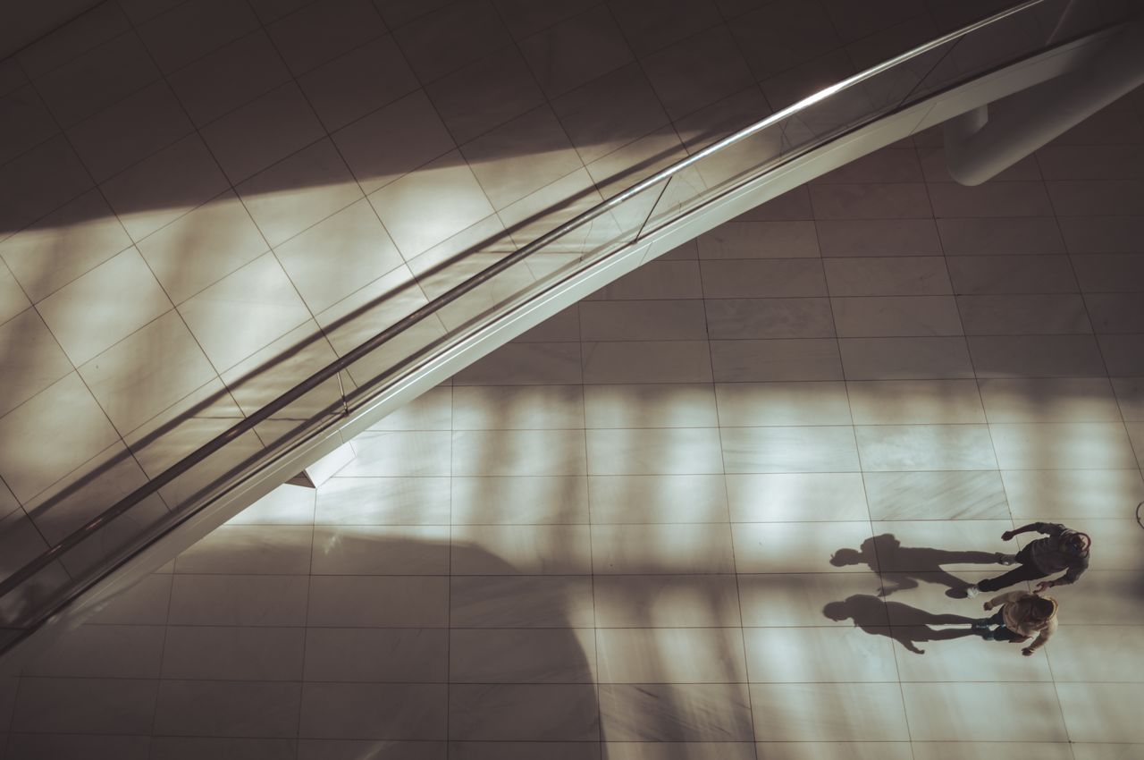 Aerial view of two people walking, casting shadows ahead of them.