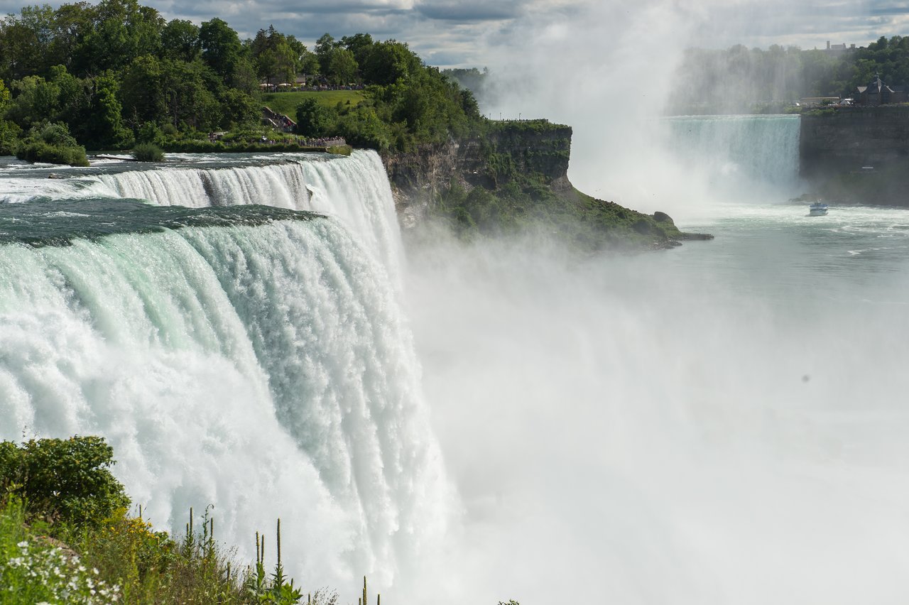 Large waterfalls cascade over a rocky edge, creating mist.