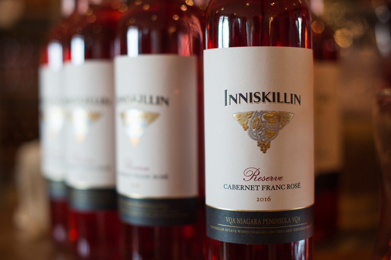 Close-up of a bottle of Inniskillin Cabernet Franc Rosé wine, with several similar bottles in the background.
