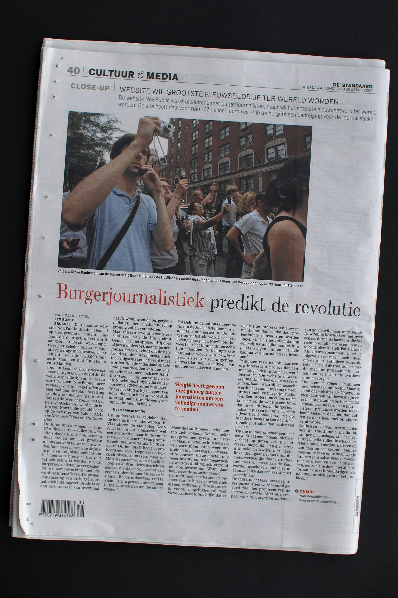 A newspaper article in De Standaard discusses NowPublic and citizen journalism, highlighting its impact on traditional media.