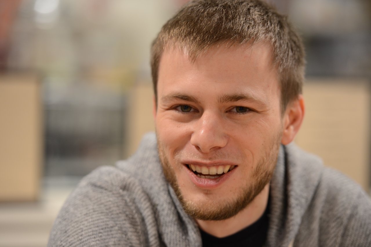 A person smiling in an indoor setting.