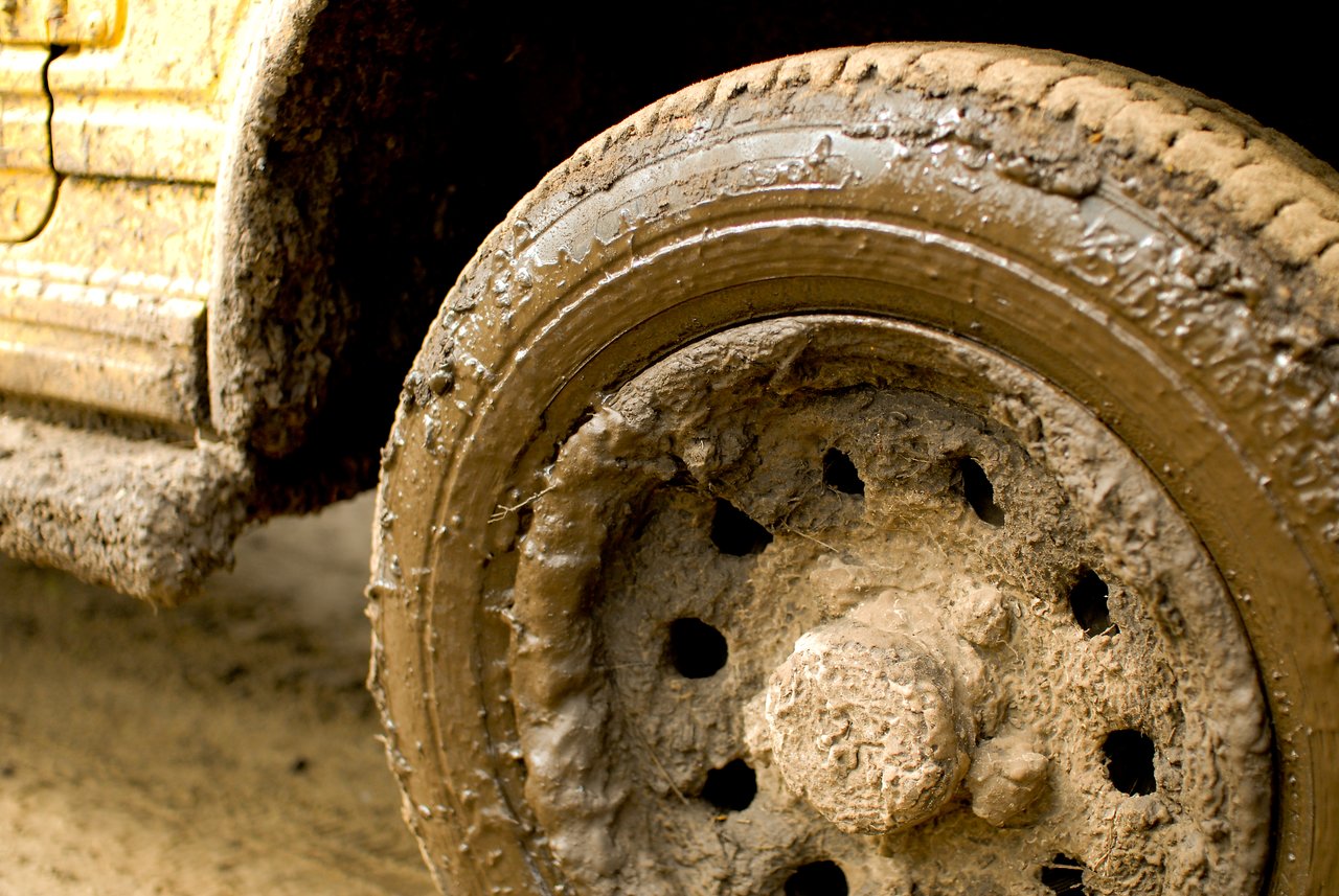 Close-up of a car wheel covered in thick mud after off-road driving.