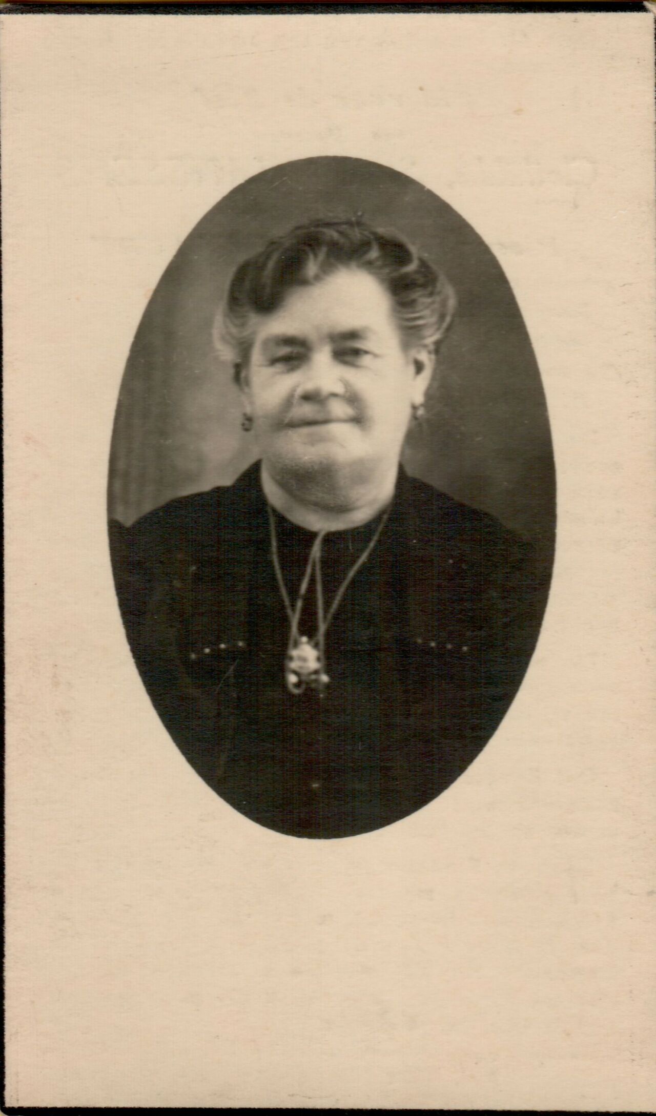 A memorial card featuring an oval-framed portrait of an older woman wearing a dark outfit and a pendant necklace.