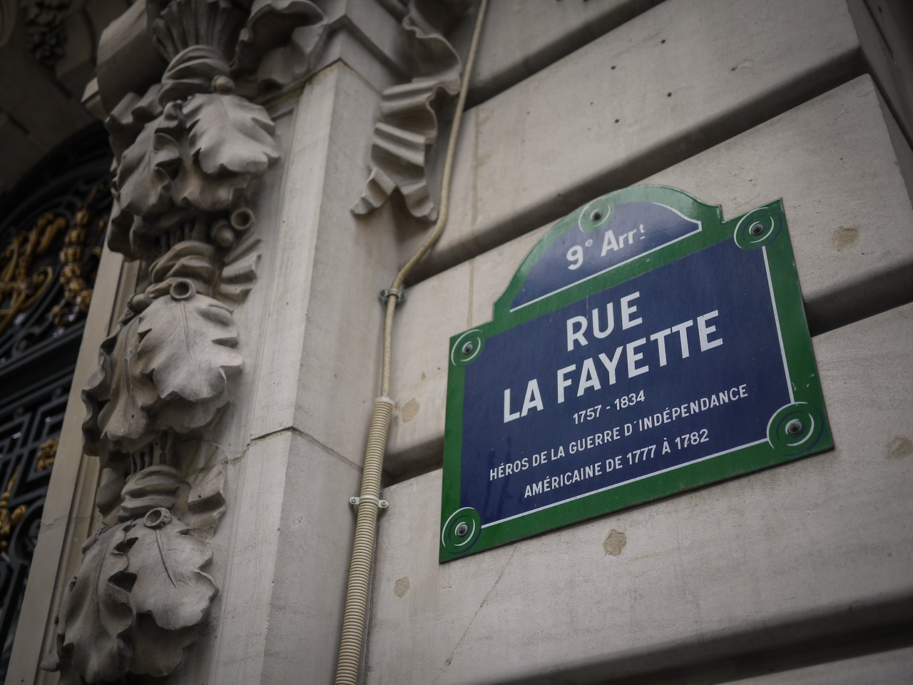 A street sign for Rue La Fayette in Paris, mounted on a stone building with decorative carvings.