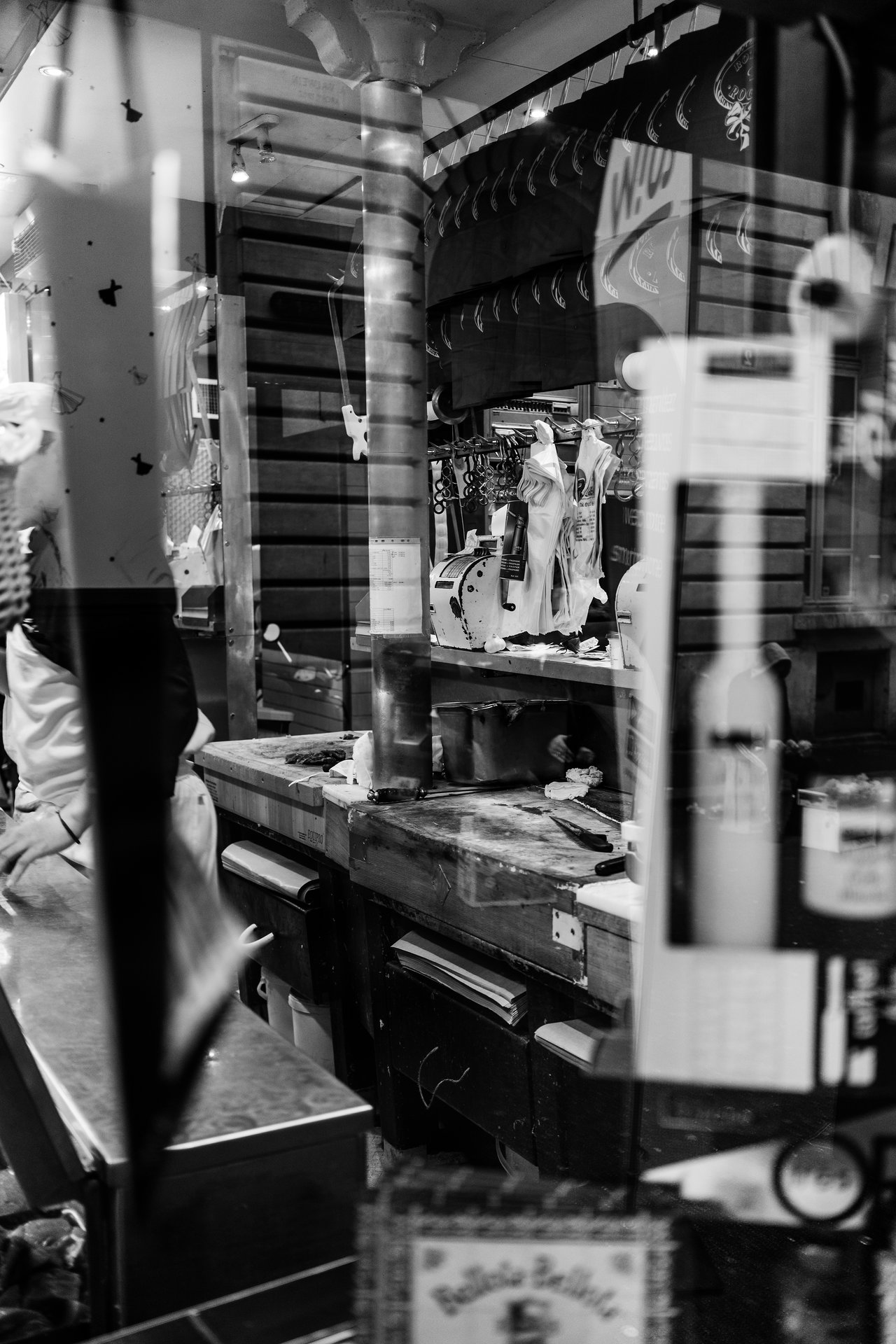 A butcher shop with a worker behind the counter, cutting meat on a worn wooden table.