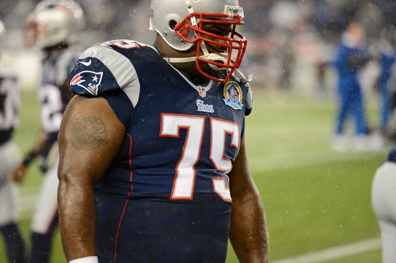 A New England Patriots player wearing jersey number 75 stands on the field during a game in the rain.