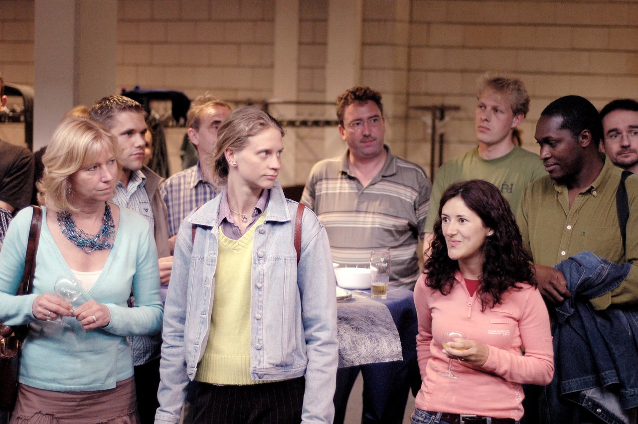 A group of people at a reception, holding drinks and engaging in conversation.
