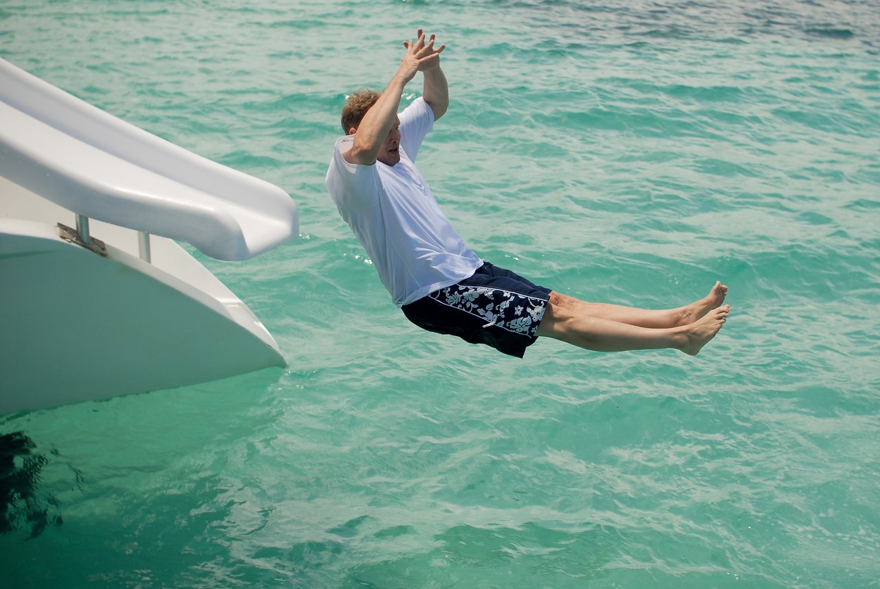 A person slides off a water slide into the ocean, arms raised and legs extended.