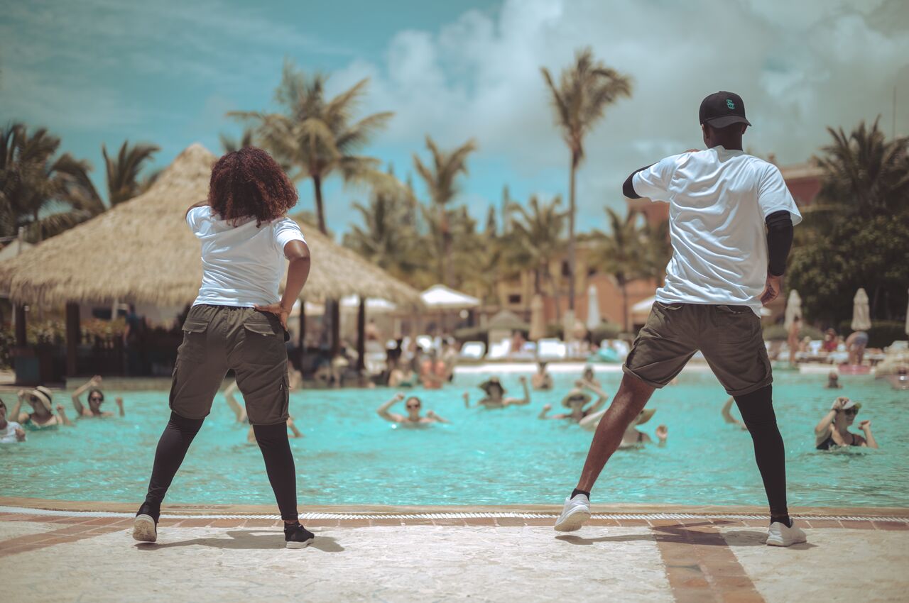Two instructors lead a water aerobics class at a resort pool.