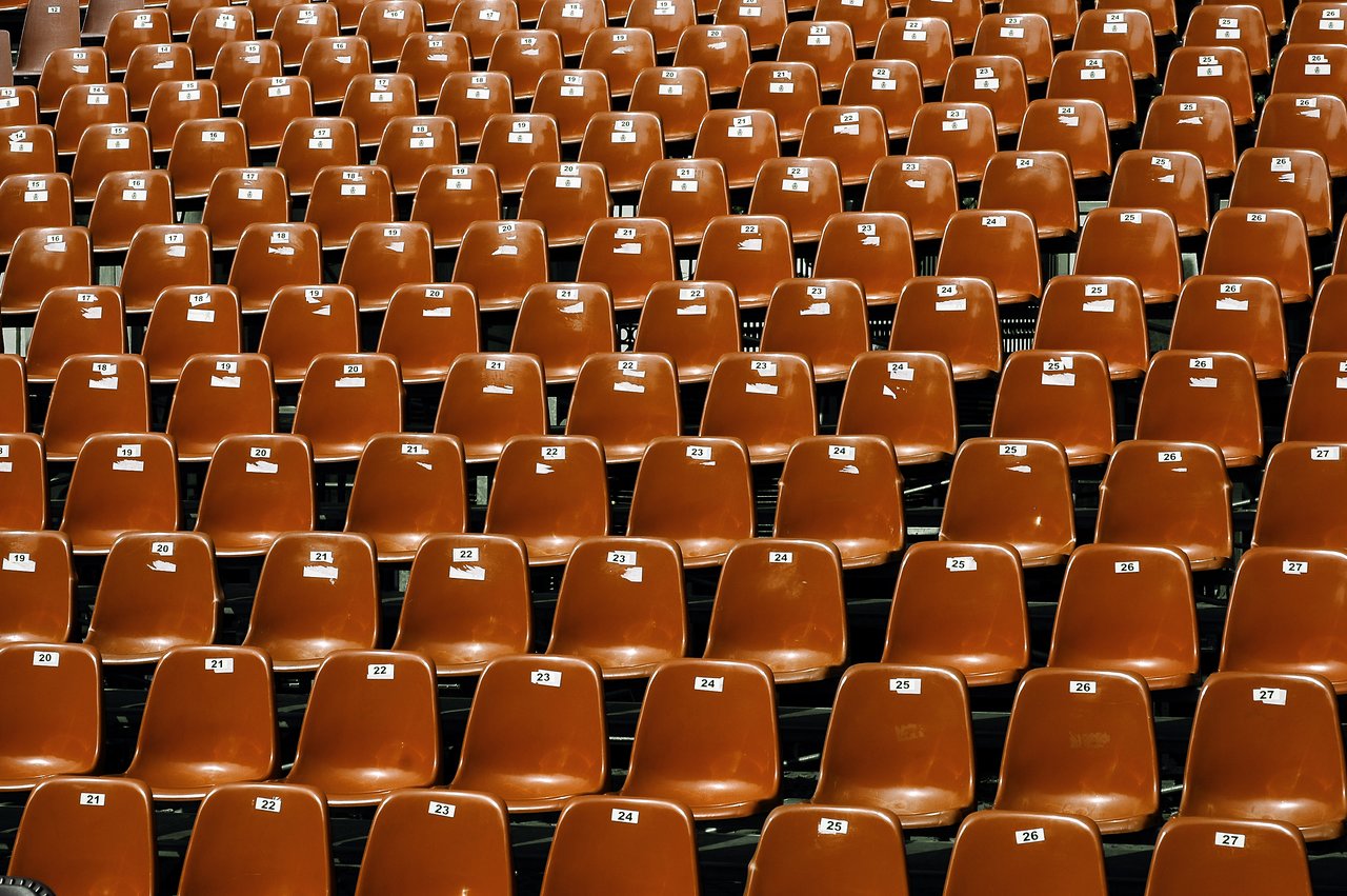 Rows of empty brown plastic chairs with numbered labels, arranged in a structured pattern.