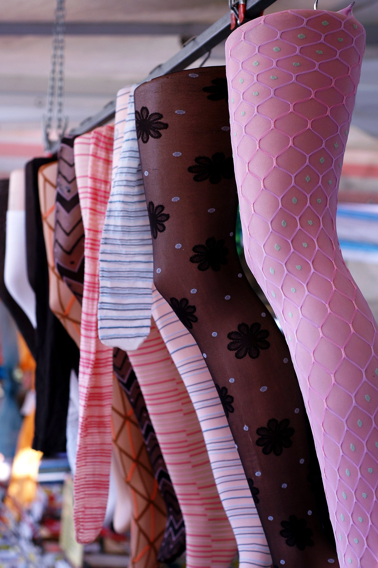 Mannequin legs wearing colorful patterned stockings hang in a row at a market display.
