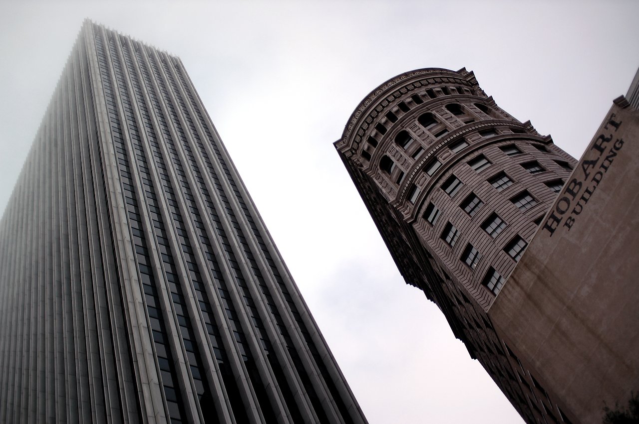 Two tall buildings in San Francisco, including the Hobart Building, viewed from below against a cloudy sky.