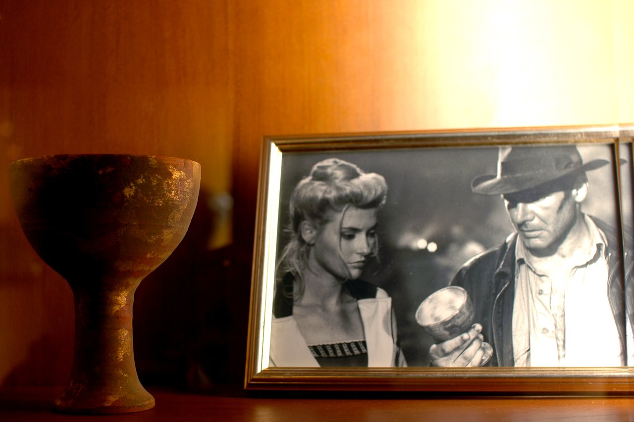 A prop Holy Grail from *Indiana Jones and the Last Crusade* displayed next to a framed movie still.