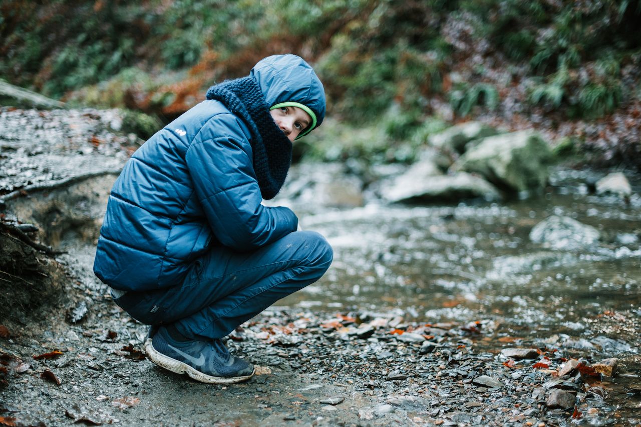 A person in a blue winter jacket crouches near a rocky stream during a hike in Ninglinspo Valley.