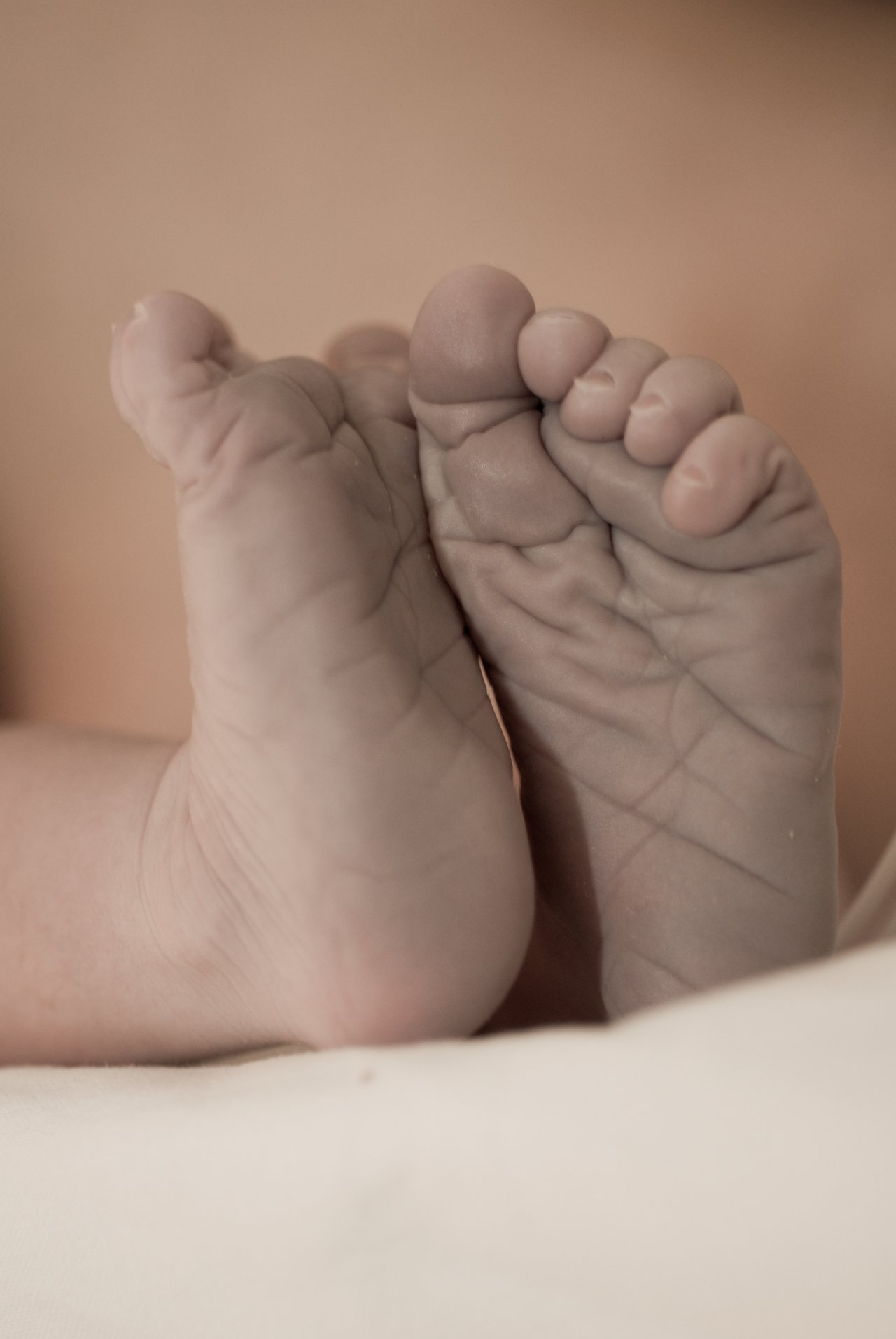Close-up of a baby's feet resting on a soft surface, showing small toes and wrinkled soles.