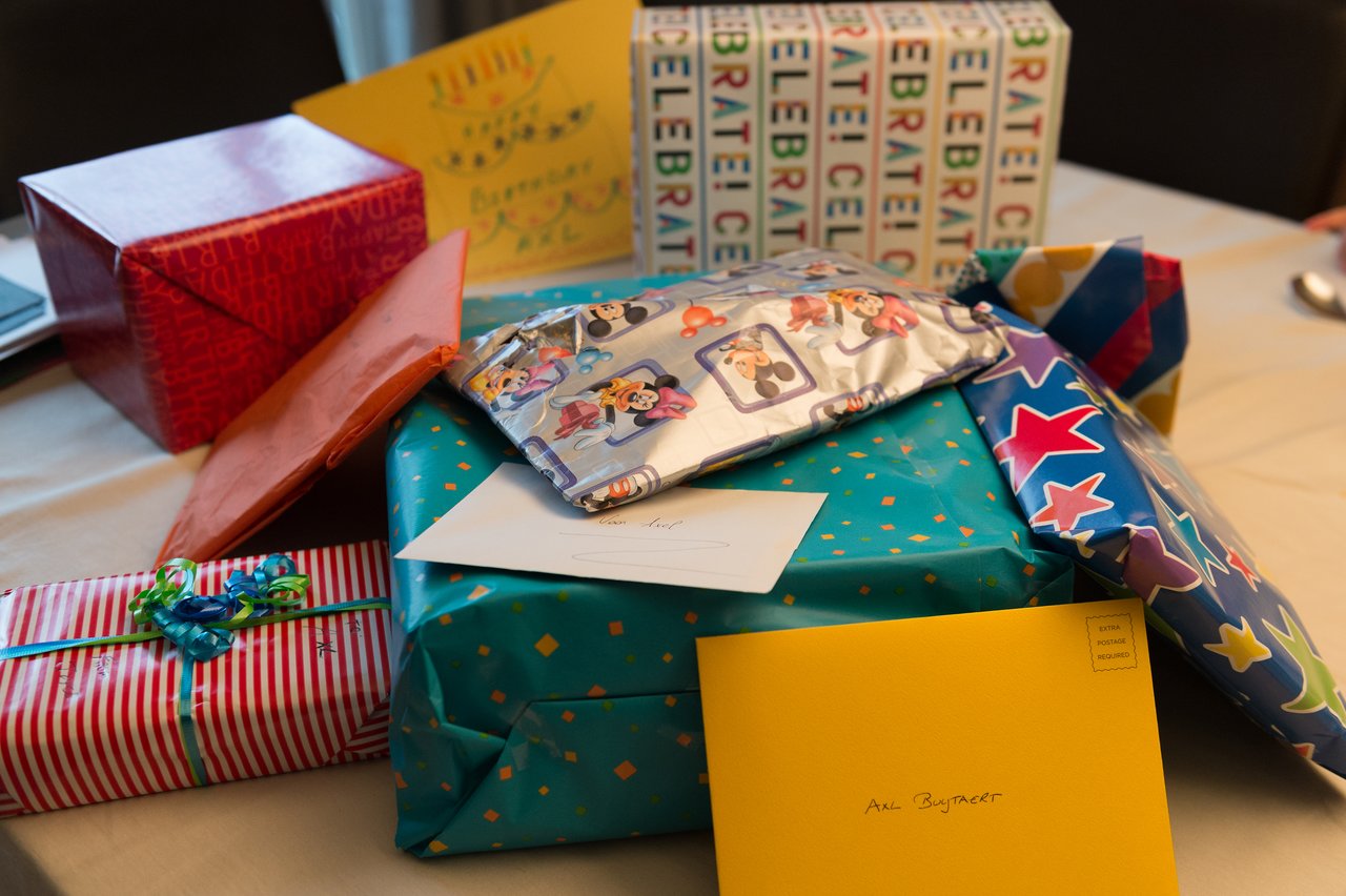 A table filled with colorful wrapped birthday presents and envelopes, including one labeled for Axl.