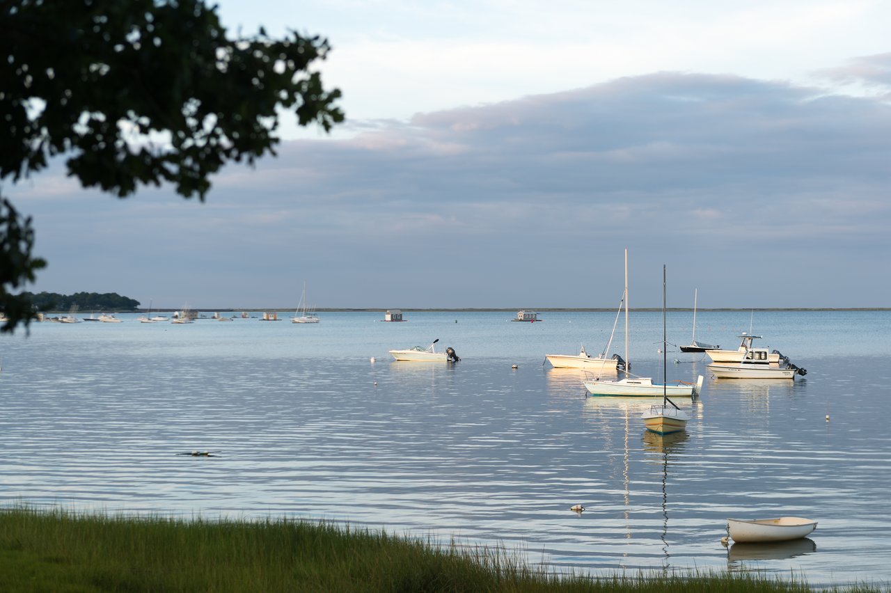 Several boats float on calm water near the shore, with a few distant structures visible on the horizon.