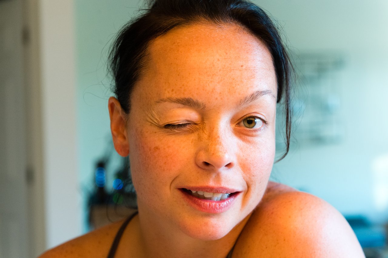 A woman with dark hair winks at the camera with a slight smile.