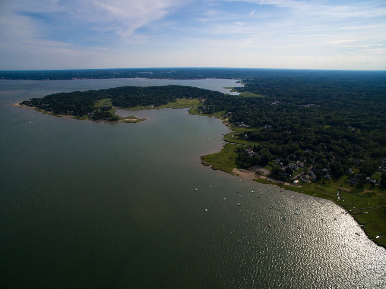 Aerial view of a coastal landscape with water, islands, and houses, captured by a drone.