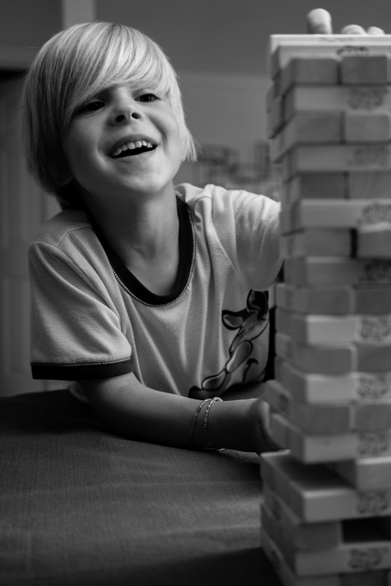 A smiling child carefully removes a Jenga block from a tall stack during a game night.