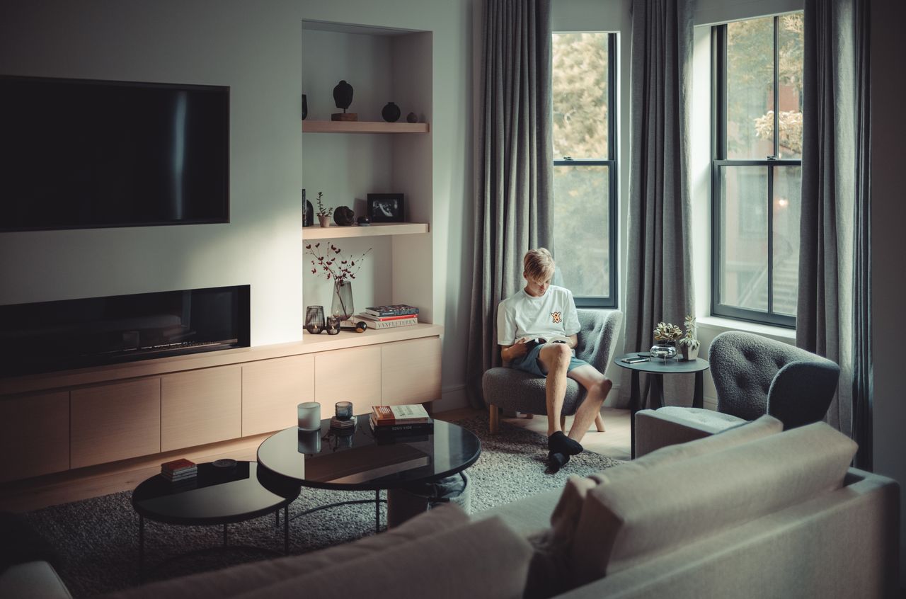 Axl sitting in a chair near a window, reading a book