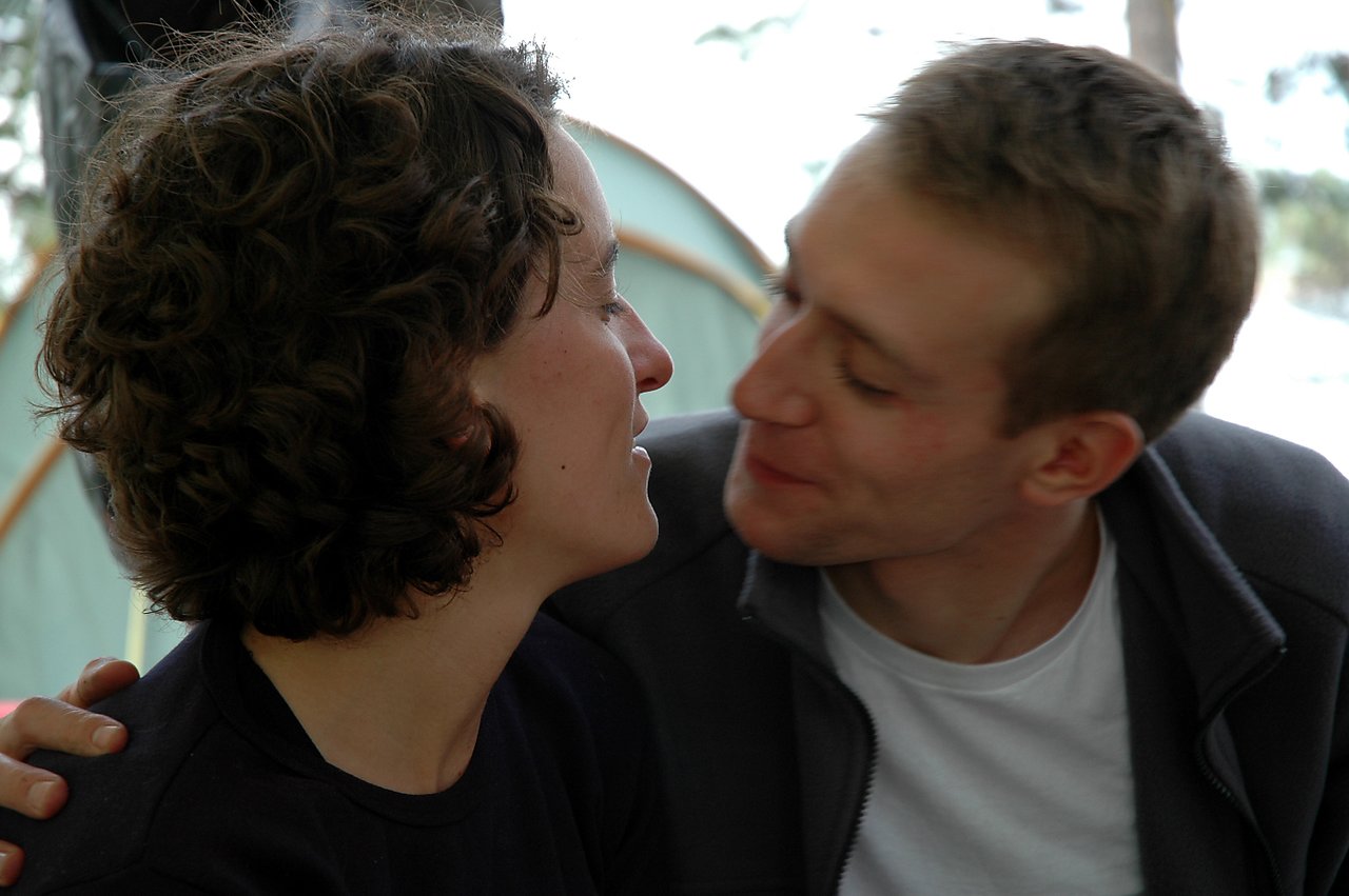 A man and woman sit closely, facing each other.