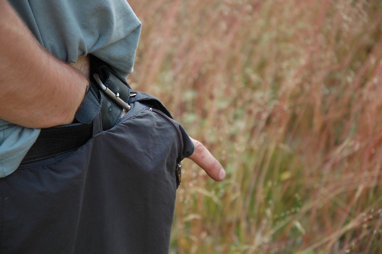 A person places their hand inside their pants, making their finger look like it is sticking out unnaturally.
