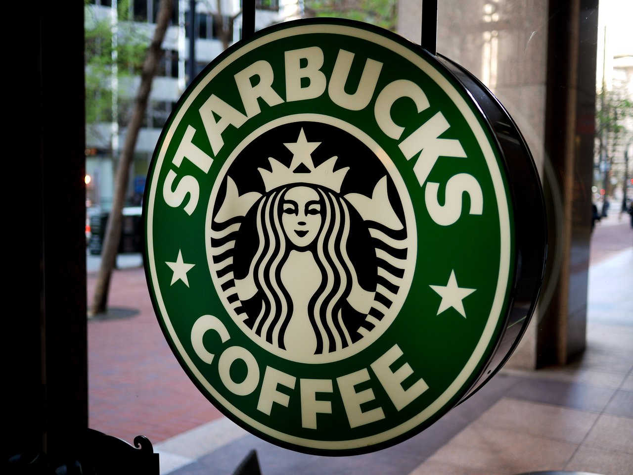 A Starbucks sign with the green and white logo is displayed on a window, facing the street outside.