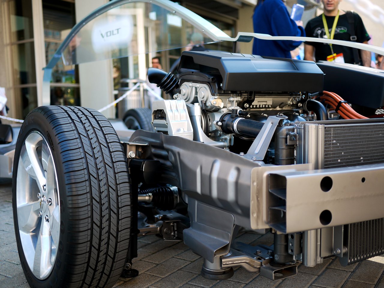 A partially assembled Chevrolet Volt chassis is displayed, showing the engine, wheels, and internal components at an event.