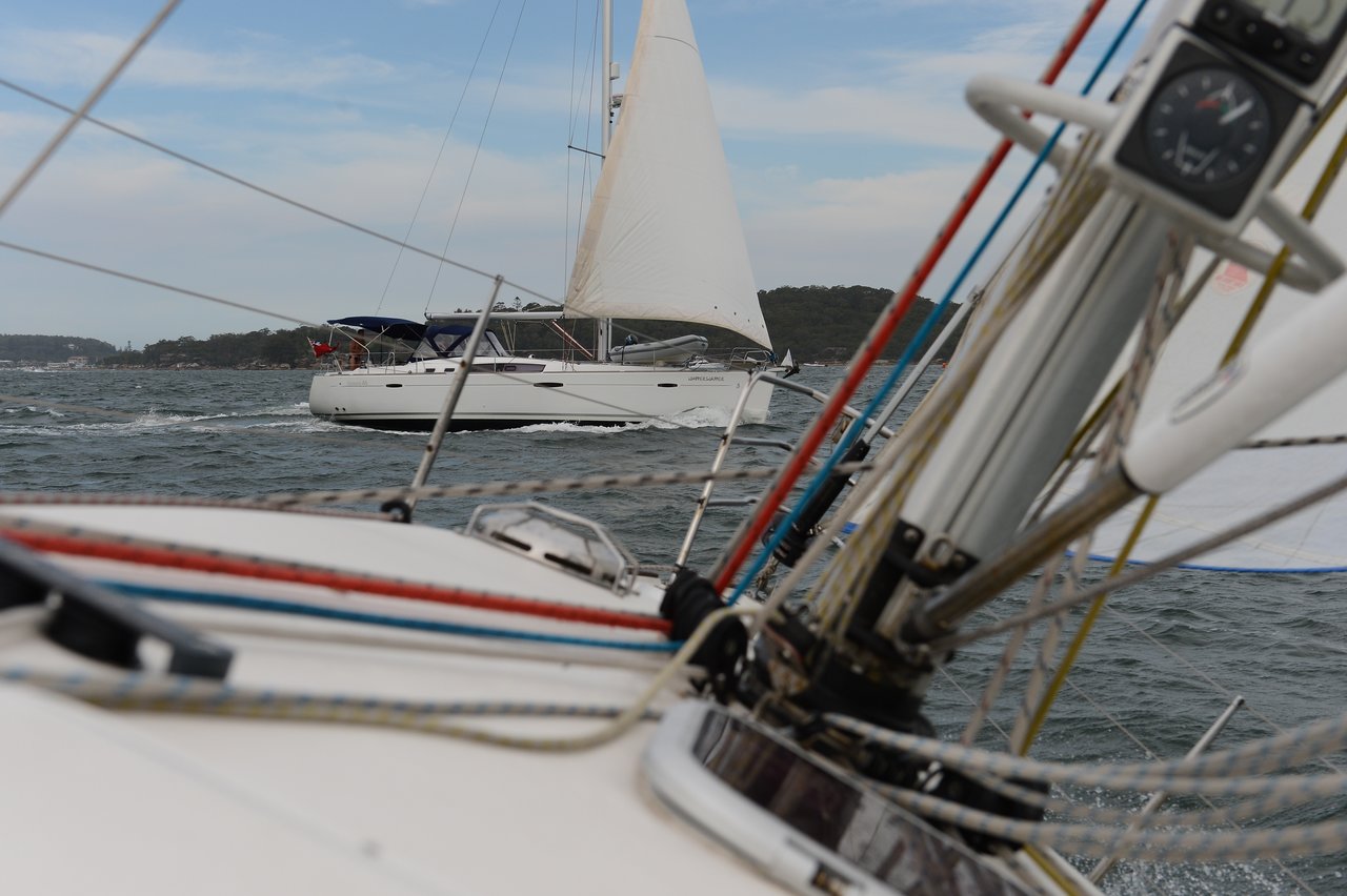 View from a sailboat, with another sailboat nearby, crossing through choppy waters just ahead.