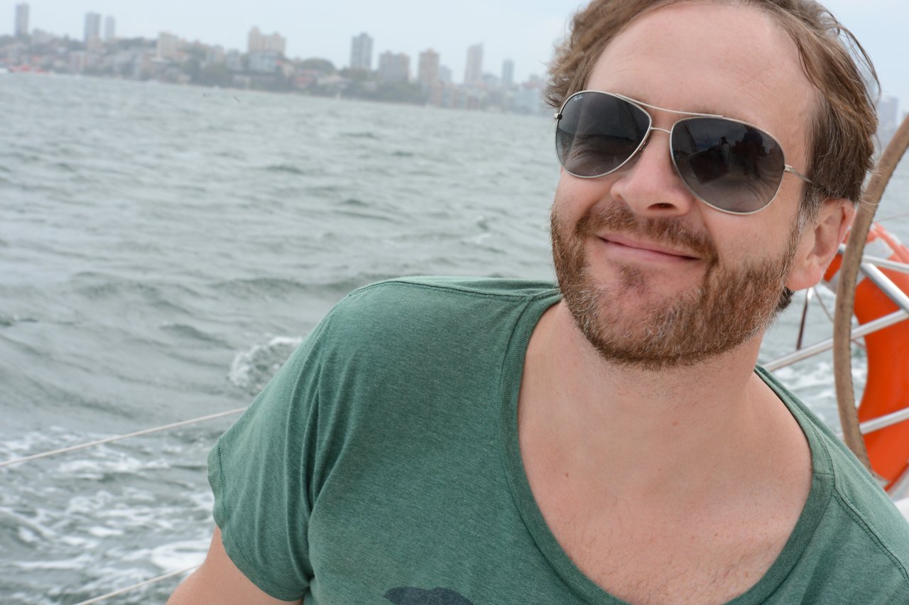 A man with a beard, wearing sunglasses and a green t-shirt.