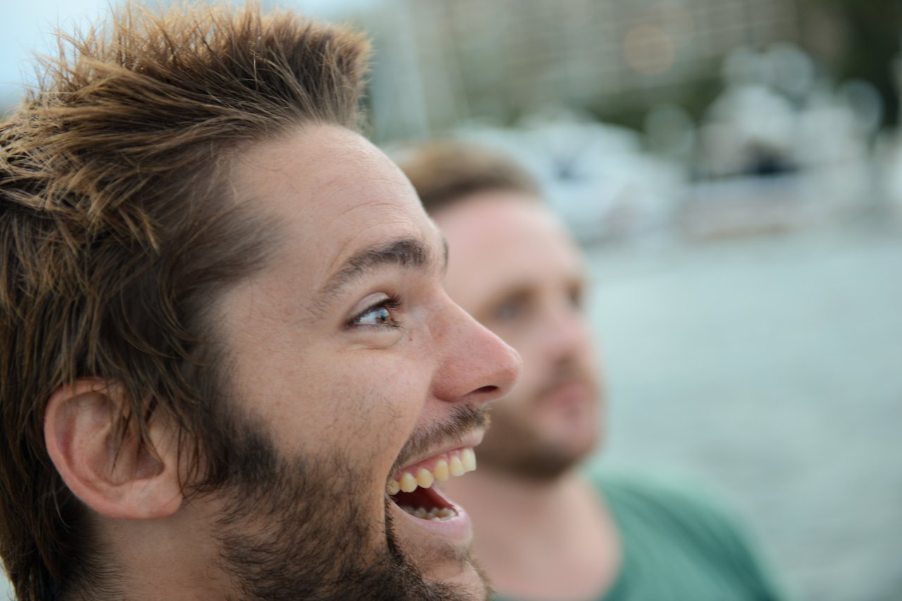 A close-up of a smiling man with short, spiky brown hair and a beard.