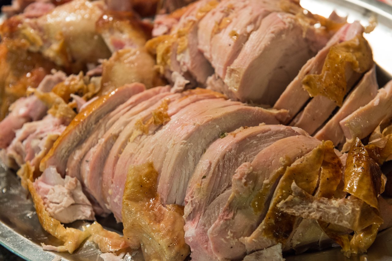 Sliced roasted turkey with crispy skin on a serving platter, prepared for a Thanksgiving meal.