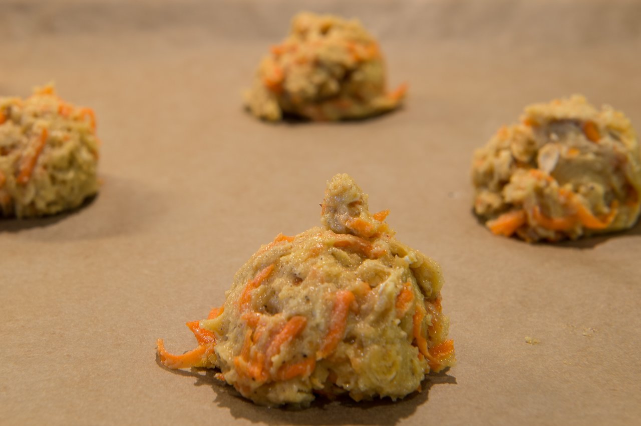Scoops of carrot cake cookie dough on a baking sheet, ready to be baked.