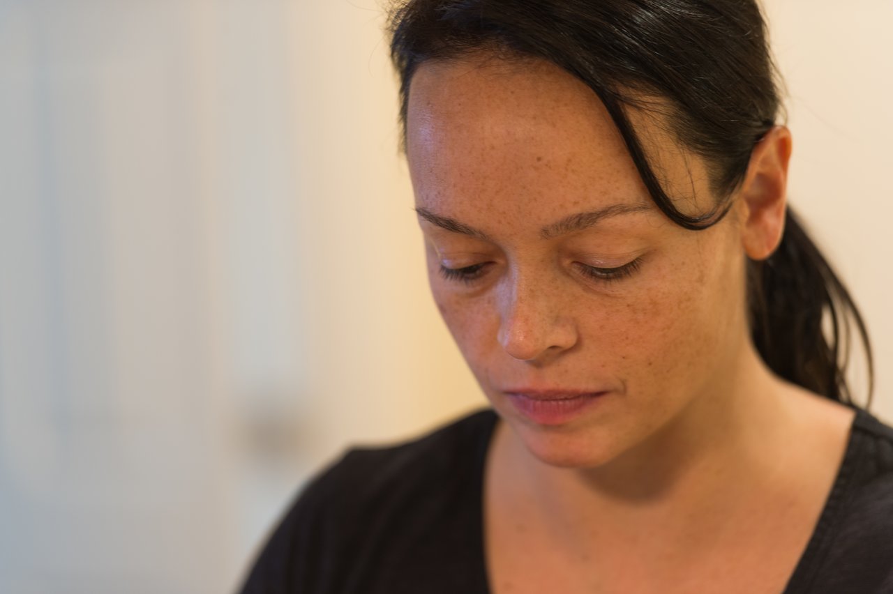 A person looking down with a focused expression, possibly preparing or handling food.