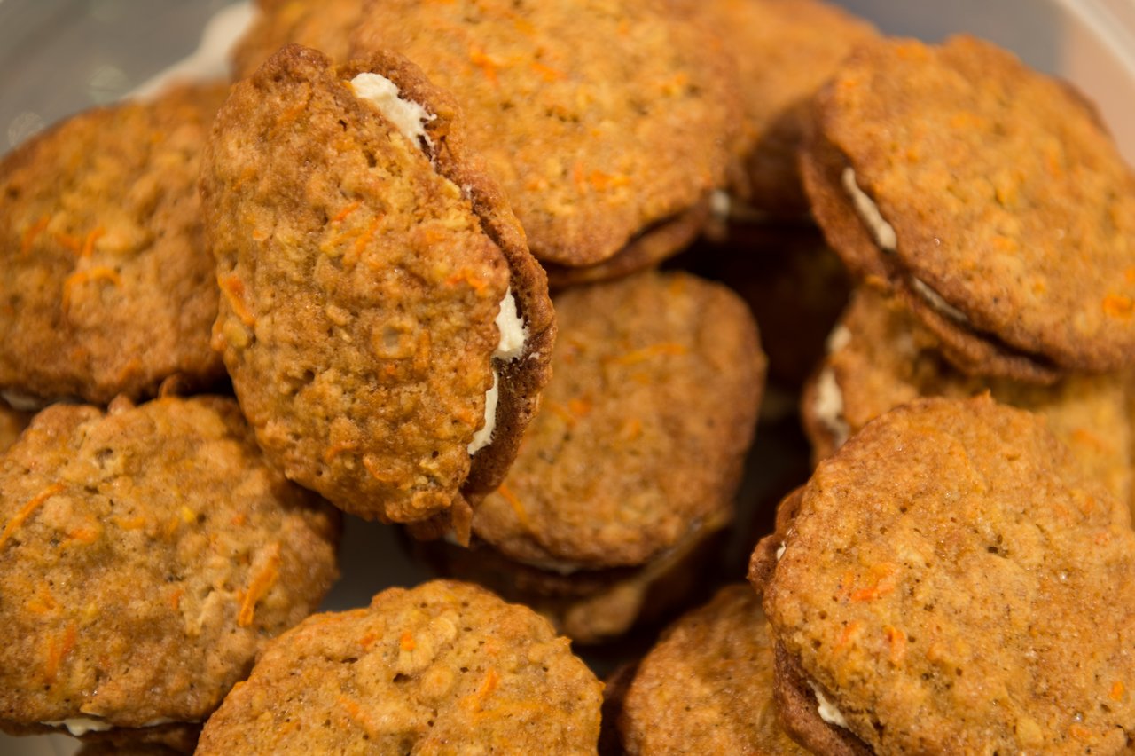 A close-up of carrot cake cookies with cream filling, stacked together in a container.