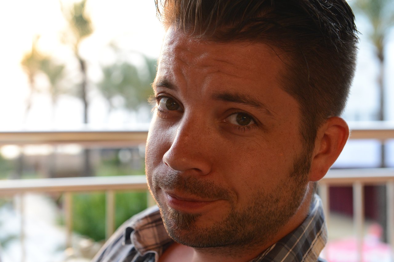A man with short hair and facial hair looks directly at the camera with a slight smile.