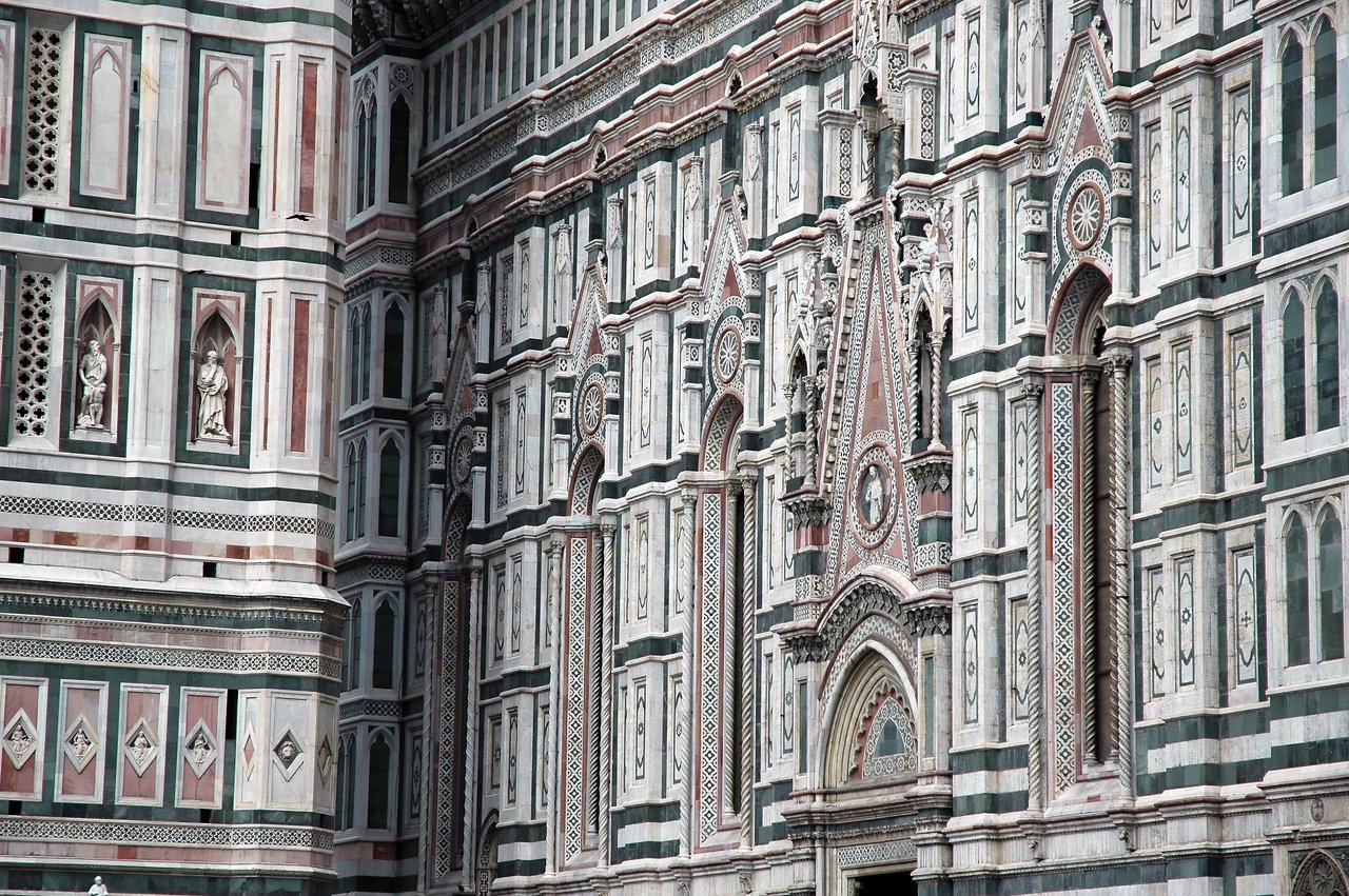 Close-up of Florence Cathedral's marble facade, featuring intricate patterns, statues, and decorative arches.